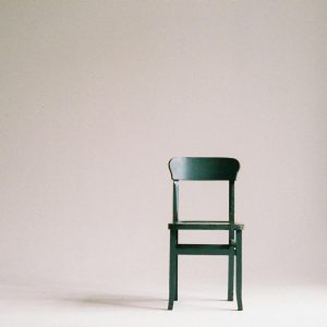 Ein einzelner schwarzer Stuhl in einer minimalistischen Studioumgebung mit neutralem Hintergrund.