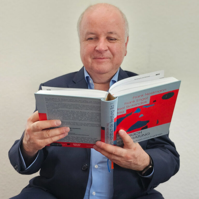 Dr. Klaus-Peter Pfeiffer von vorne mit seinem Buch in der Hand.
